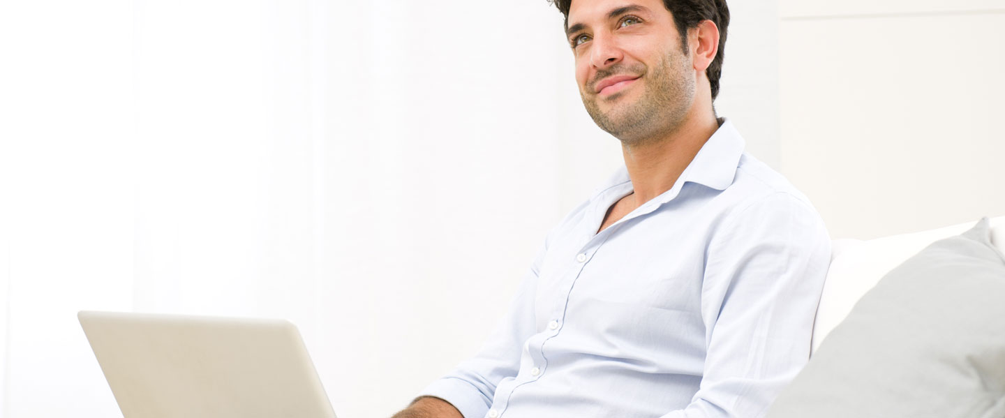entspannte Frau im Sessel mit Laptop auf dem Schoß